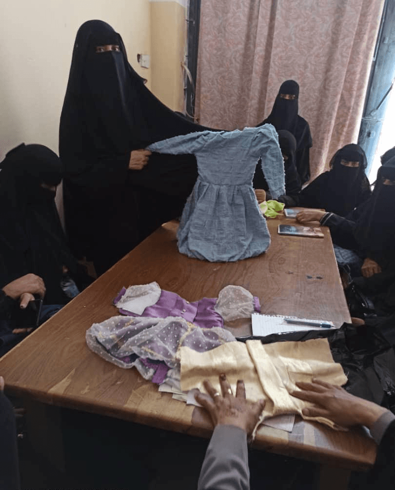 Students showing a child’s dress they made