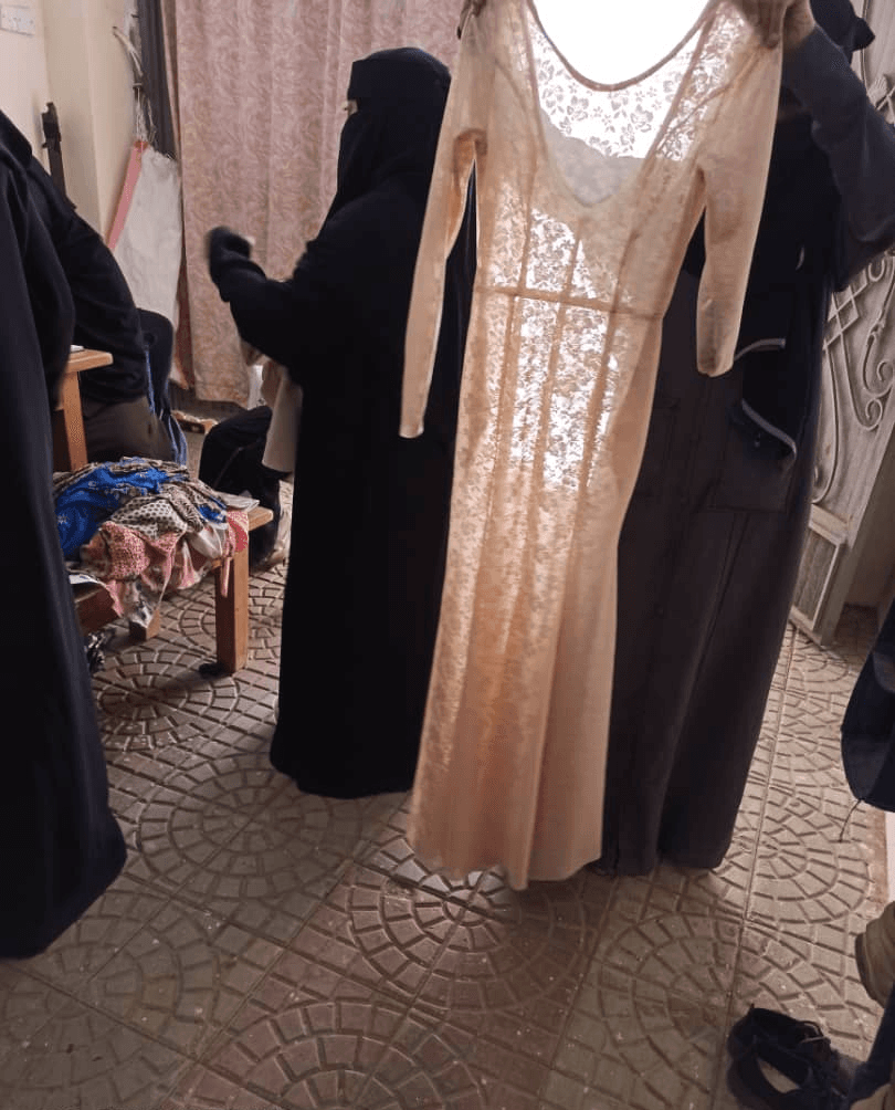 Students holding up a long lace evening dress
